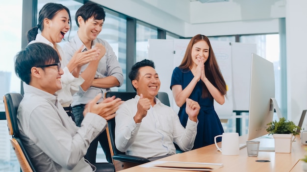 Free photo millennial group of young businesspeople asia businessman and businesswoman celebrate giving five after dealing feeling happy and signing contract or agreement at meeting room in small modern office.
