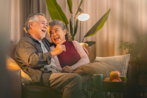 Free photo old retired age asian couple watching tv at homeold mature asian couple cheering sport games competition together with laugh smile victory on sofa couch at living room home isolation activity