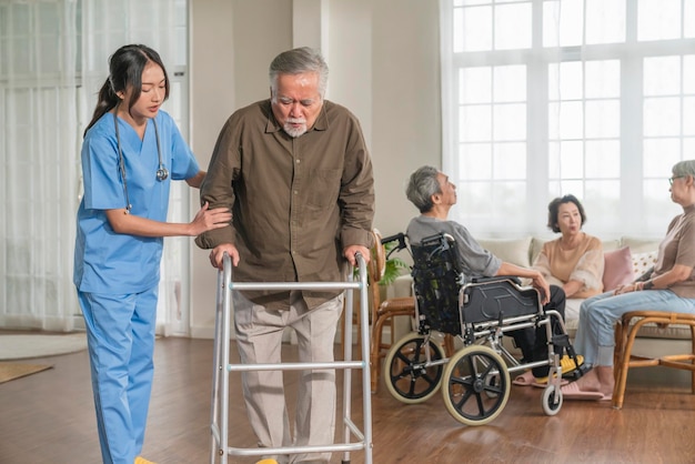 Free photo young asian female nurse care giver helping asian senior old man with mobility walker in living area of nursing home senior daycare centernurse take care elderly patient with cheerful concentrate
