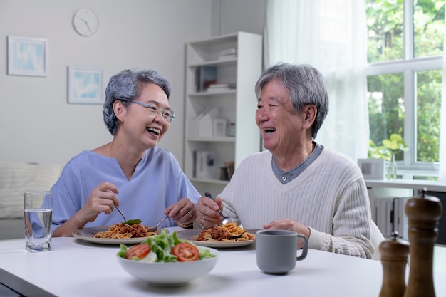 Photo happy asian senior couple eating meal together in kitchen at home retirement senior couple lifestyle living concept