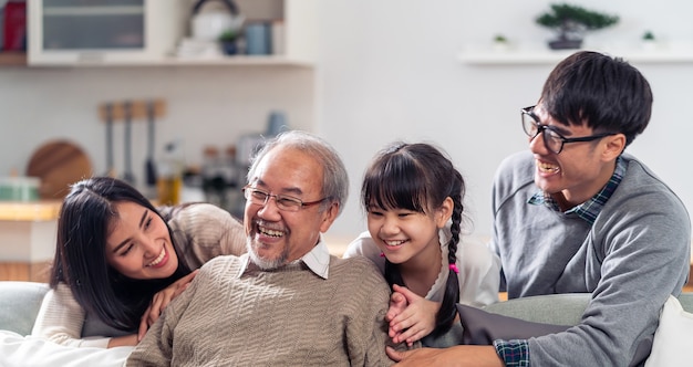 Photo panorama group portrait of happy multigenerational asian family sit on sofa couch in living room with smile.