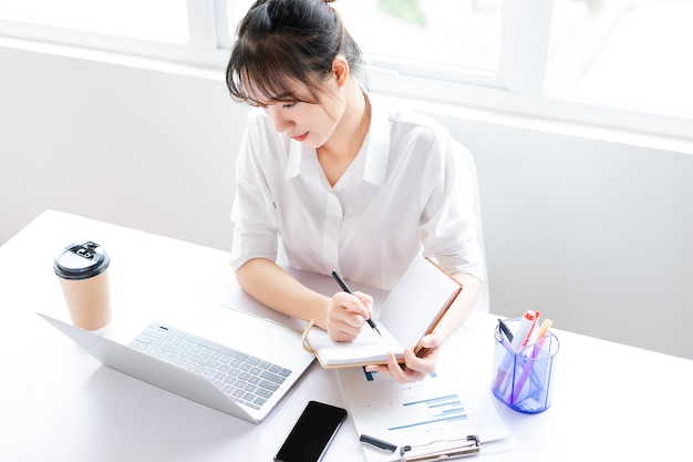 Photo portrait of young businesswoman sitting and making plans in a notebook