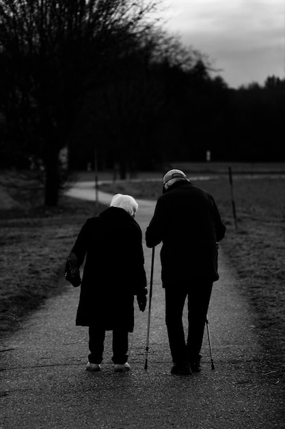 Free photo vertical grayscale shot of old spouses walking in the park  - aging concept
